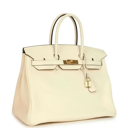 Cream leather tote with gold hardware lock, front flap, and top handles