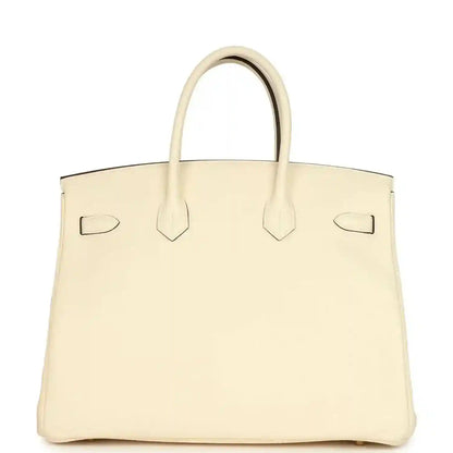 Cream leather tote with corner straps and gold turn-lock on front
