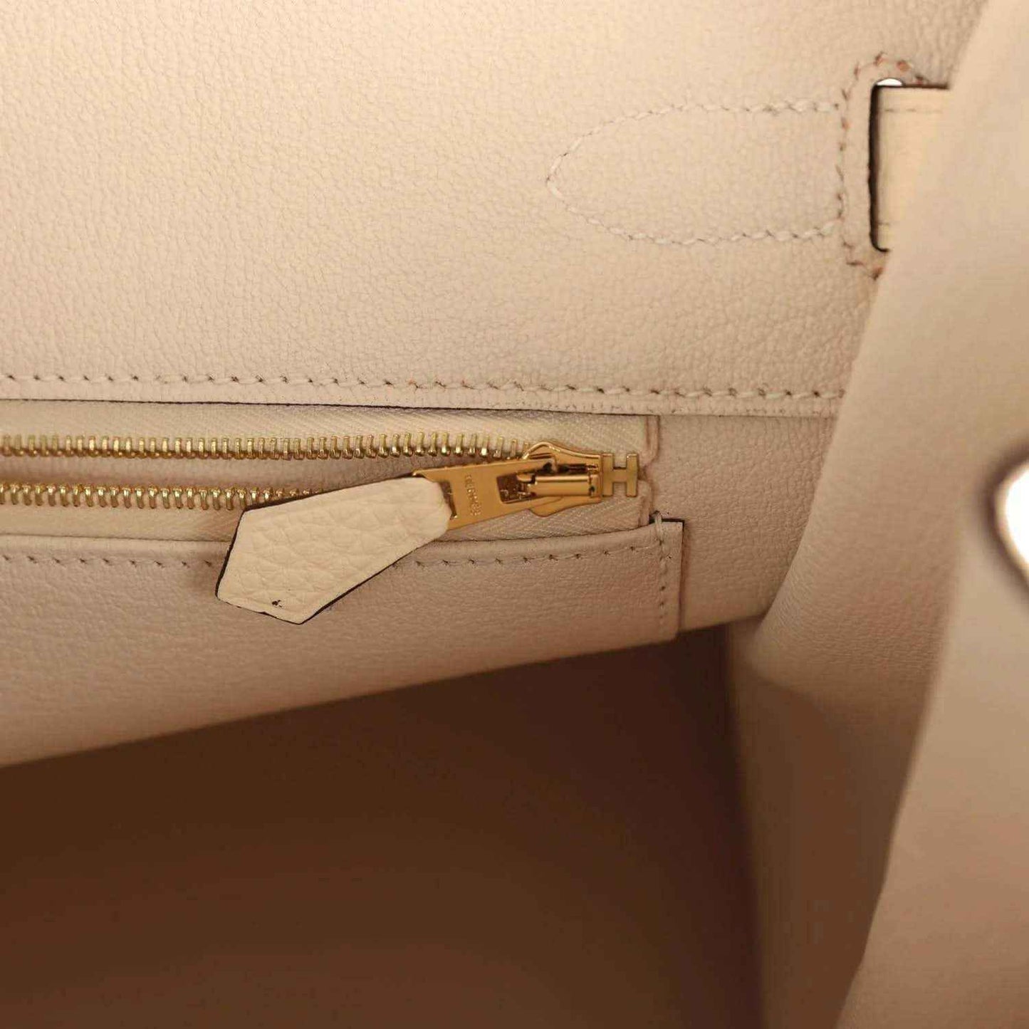 Cream leather interior pocket with gold zipper pull and leather tab