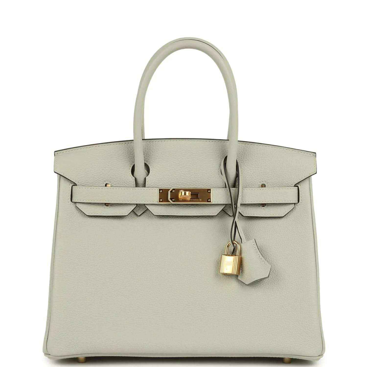 Light gray structured leather handbag with top handles, front flap, and gold lock clasp