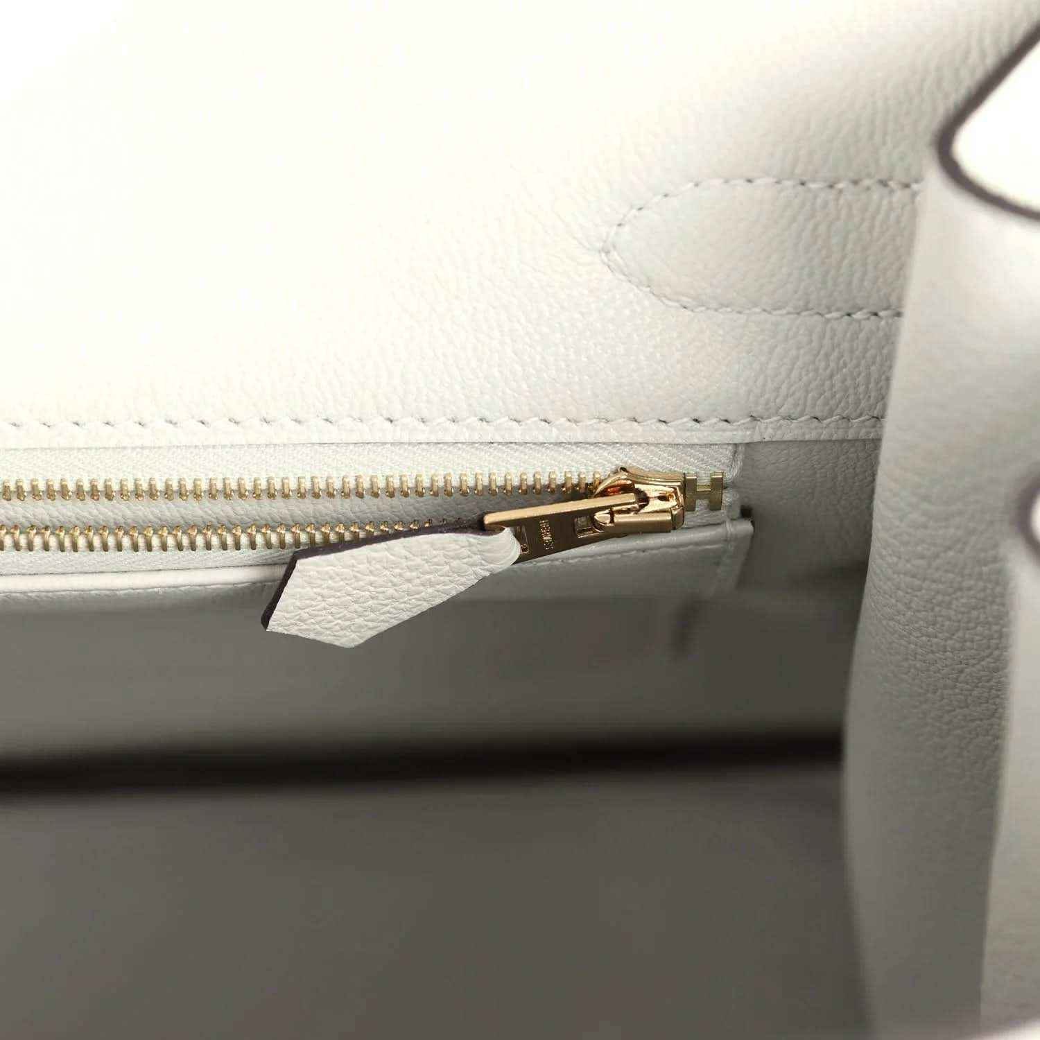 Light gray leather handbag interior with gold zipper and small hardware clip