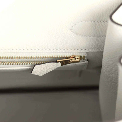 Light gray leather handbag interior with gold zipper and small hardware clip
