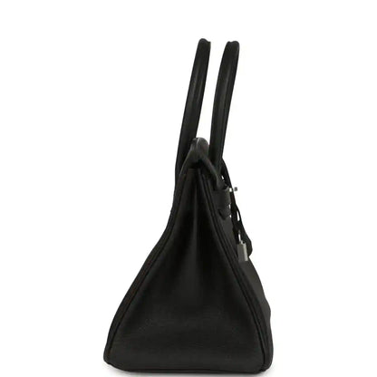 Black leather handbag side view with tall handles, gusseted bottom and hardware.