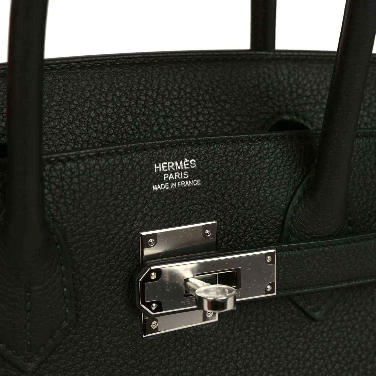 Hermès interior stamp and palladium lock hardware on black leather handbag.