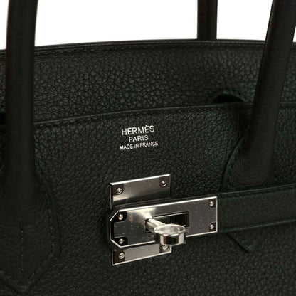Hermès interior stamp and palladium lock hardware on black leather handbag.