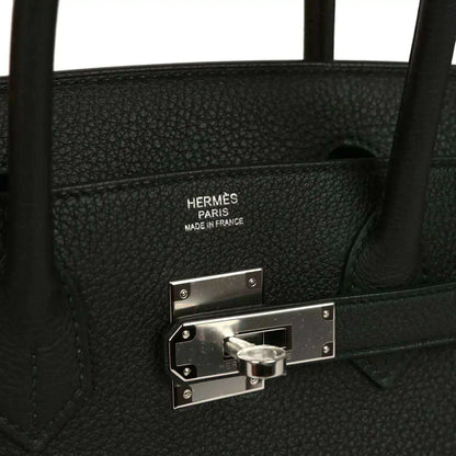 Hermès interior stamp and palladium lock hardware on black leather handbag.