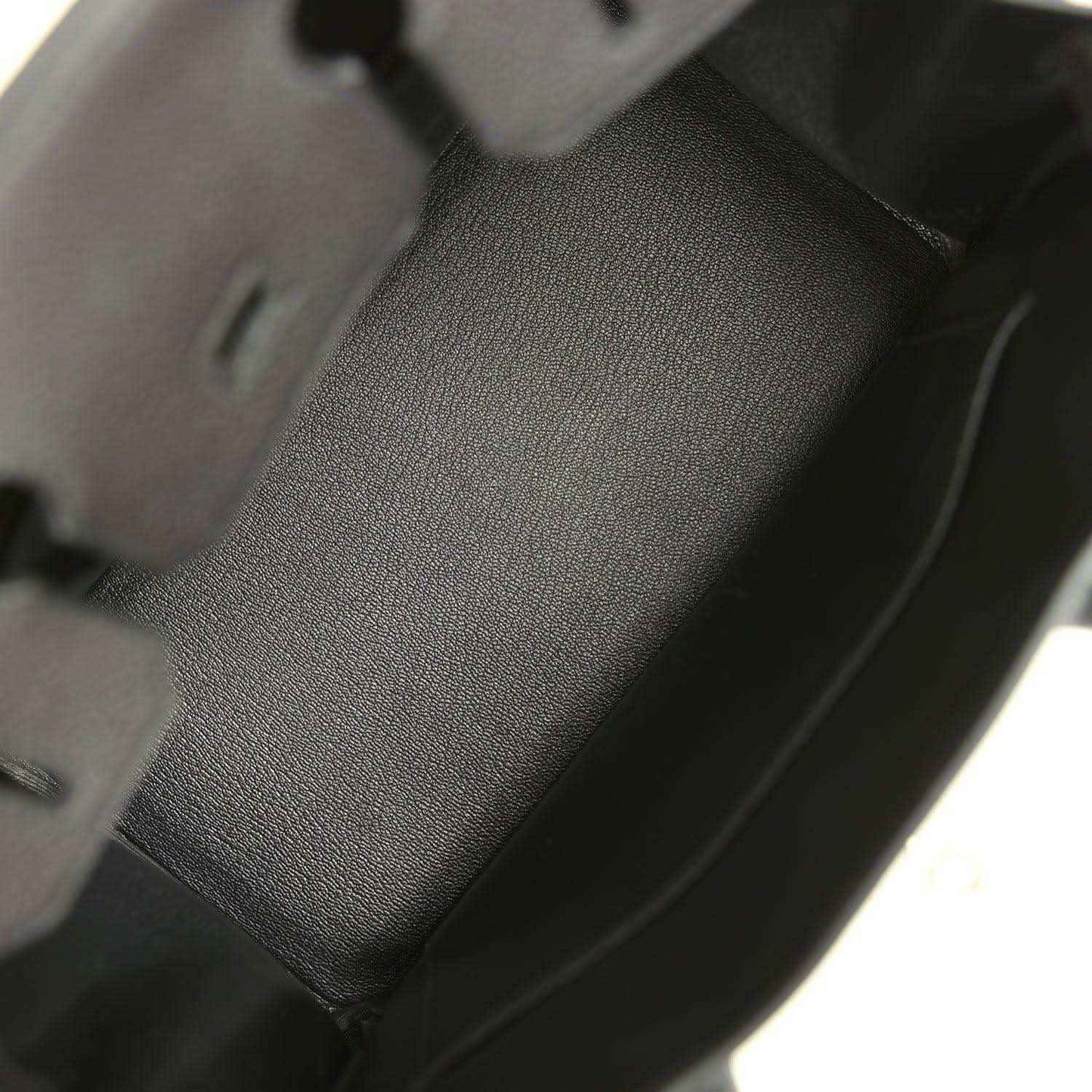 Black leather handbag interior panel with textured grain and stitched edge seams.