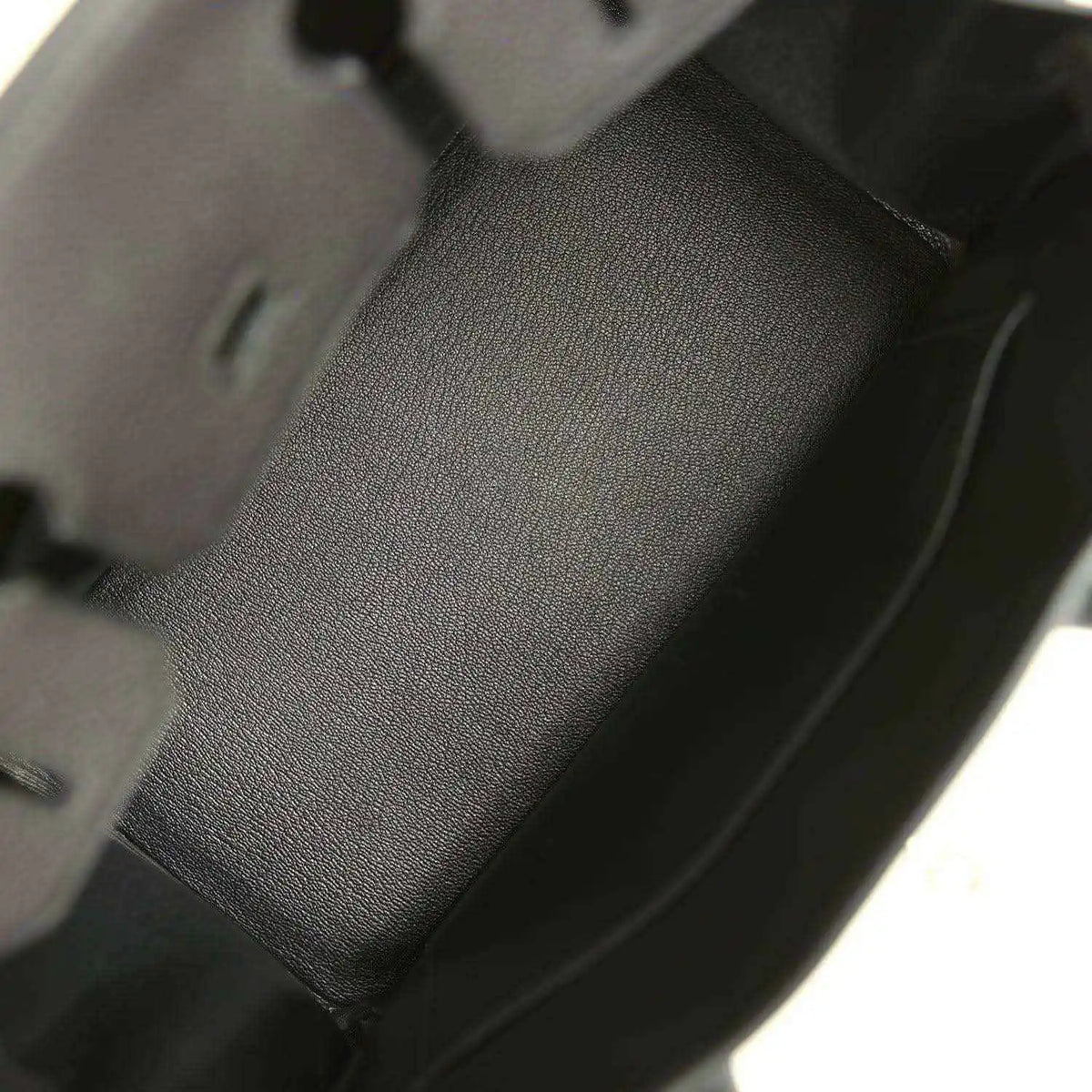 Black leather handbag interior panel with textured grain and stitched edge seams.