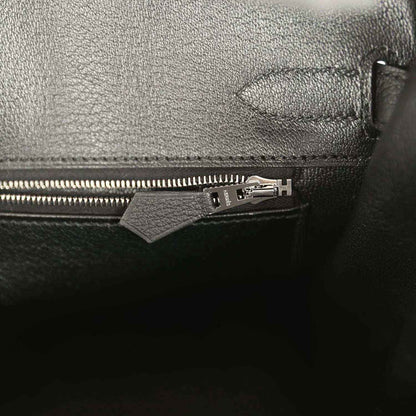 Black leather handbag pocket with zipper pull and metal hardware.