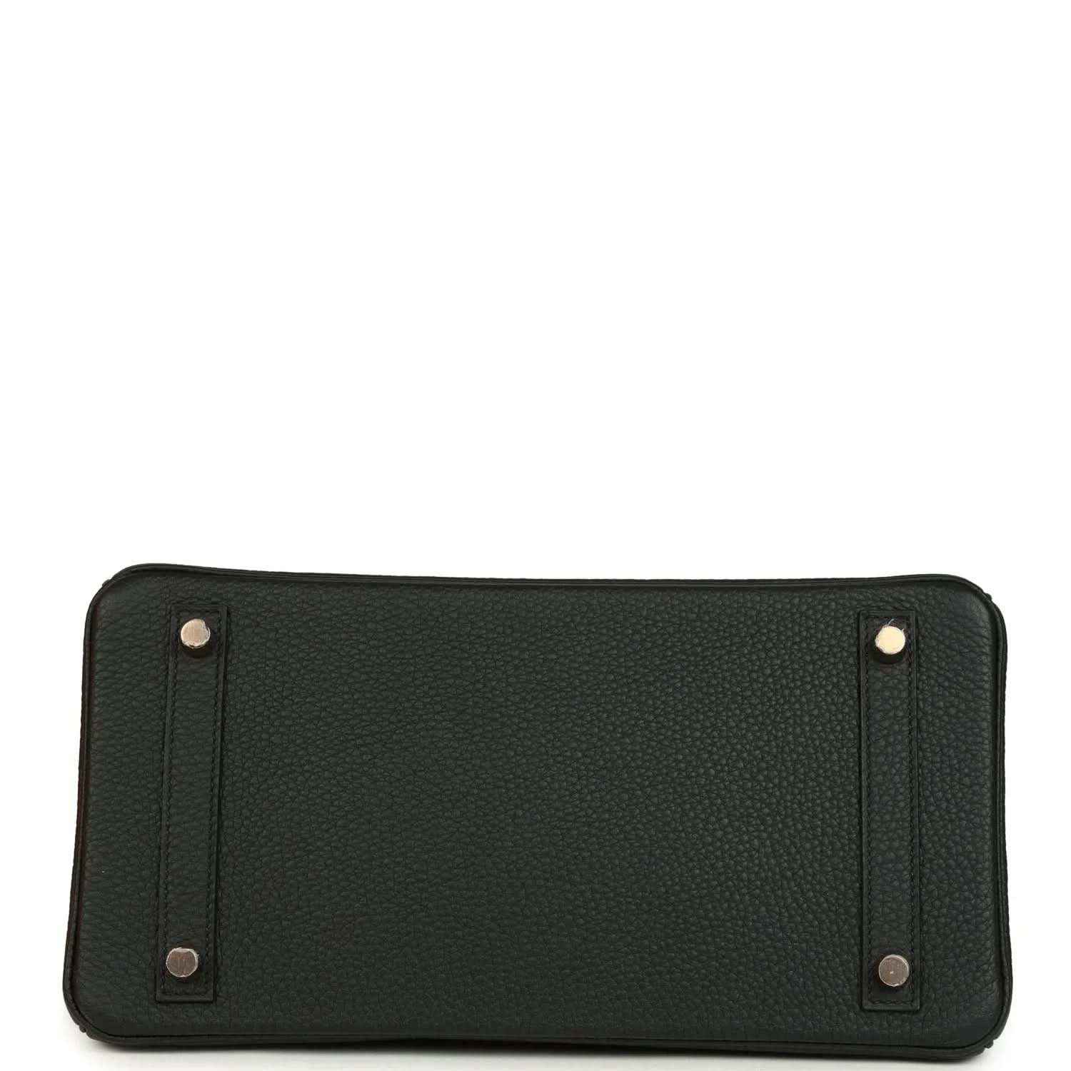 Dark green leather handbag with metal corner details and snap-secured panels