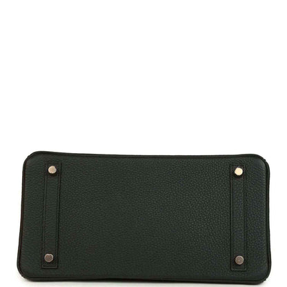 Dark green leather handbag with metal corner details and snap-secured panels