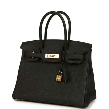 Black leather handbag with front flap, gold clasp, and dangling padlock