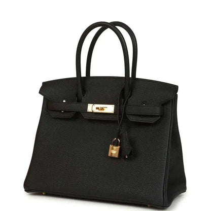 Black leather handbag with front flap, gold clasp, and dangling padlock