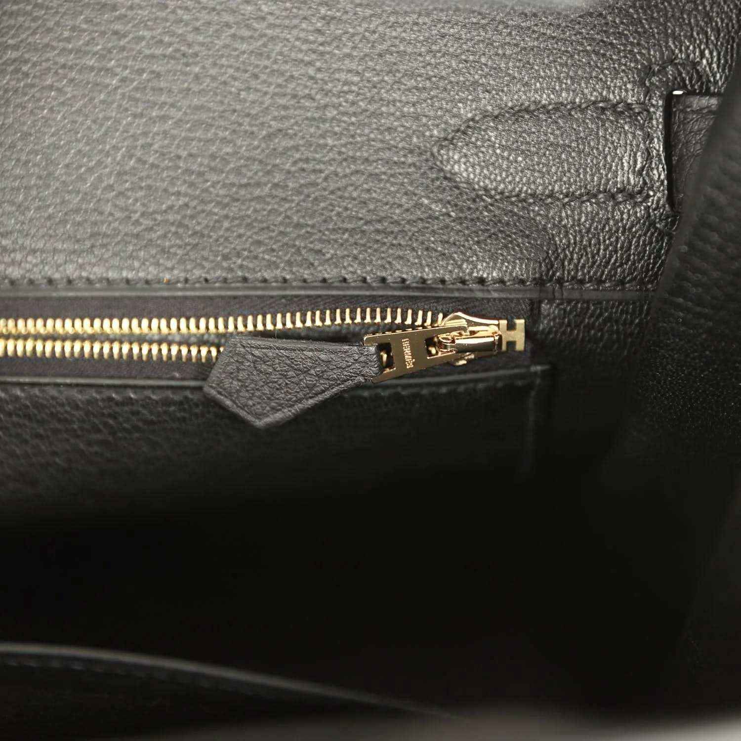 Black leather handbag interior with gold zipper and stitched pocket