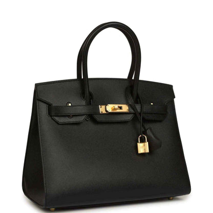 Black leather handbag with top handles, gold clasp, and hanging padlock charm