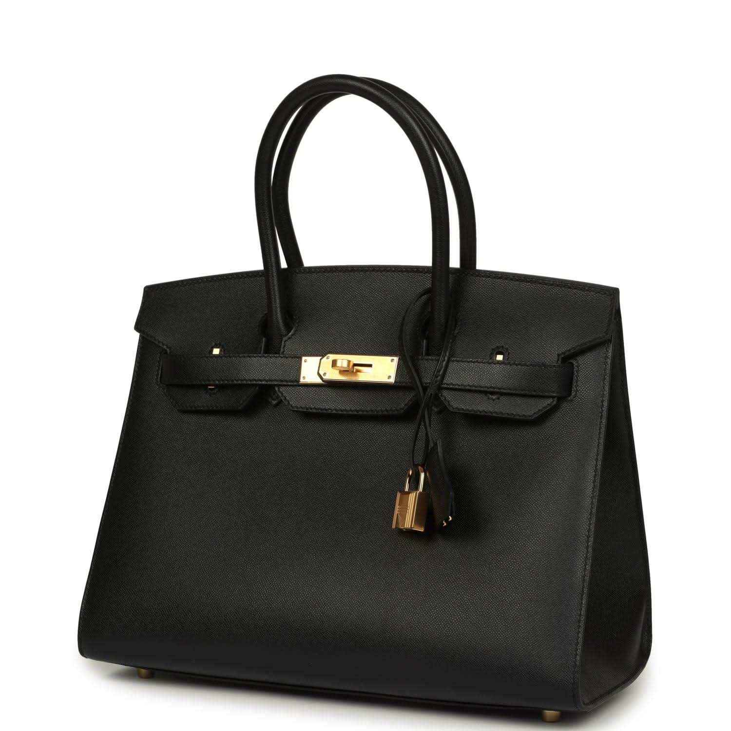 Black leather handbag with top handles, gold front clasp, and hanging tassel