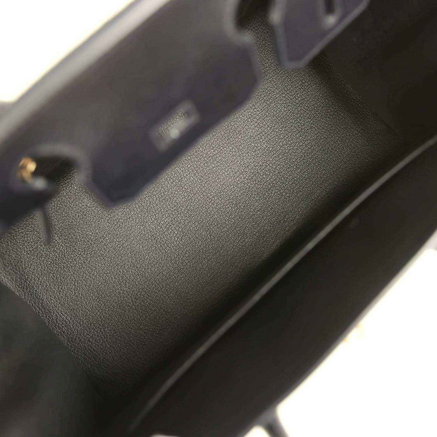 Black leather handbag interior with stitched edge and small gold hardware detail