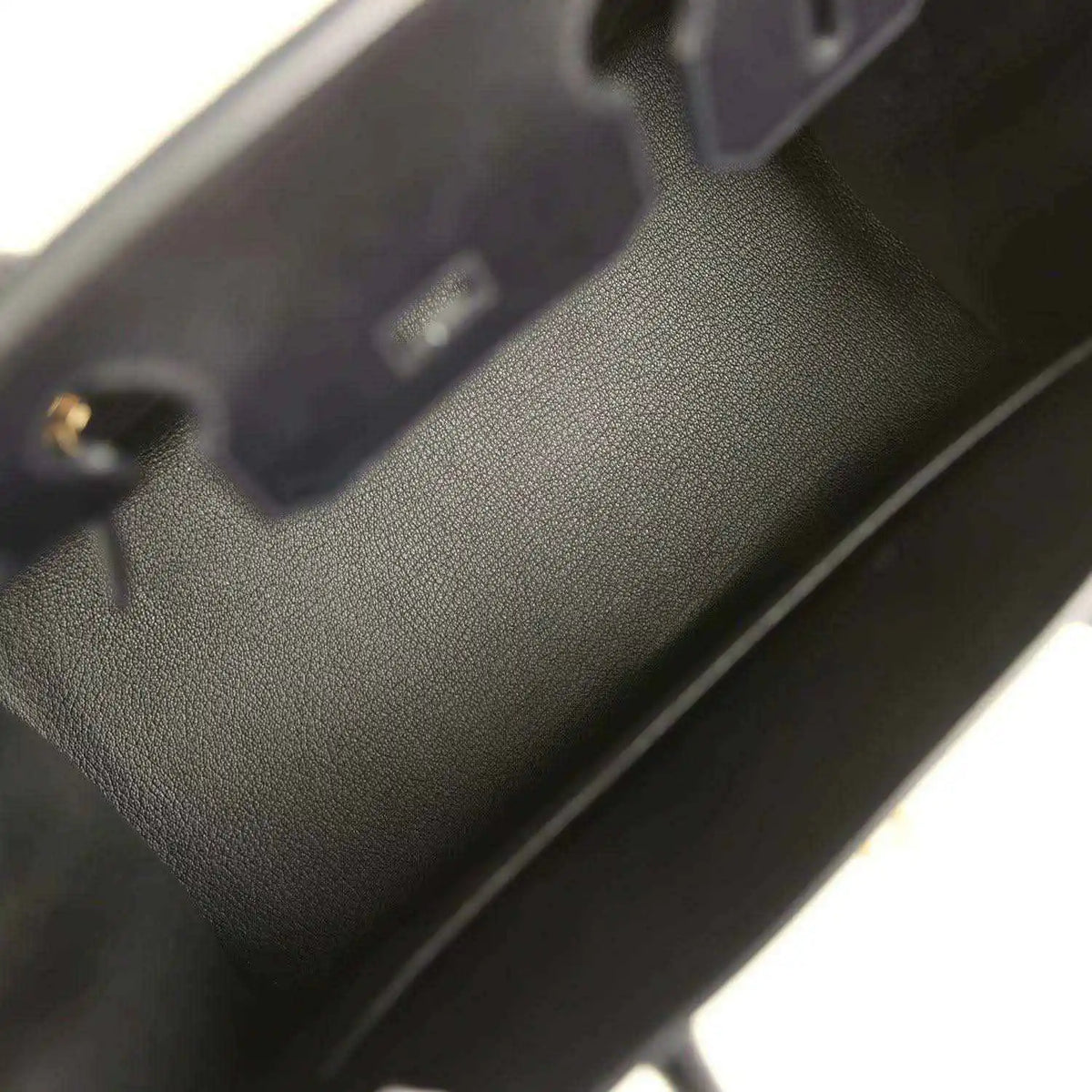 Black leather handbag interior with stitched edge and small gold hardware detail