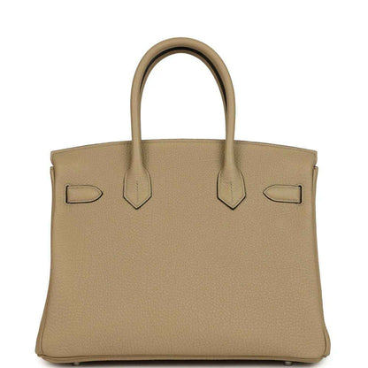 Tan leather handbag front view with flap, decorative straps, and polished lock bar