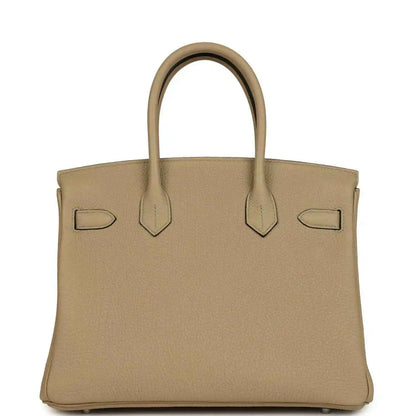 Tan leather handbag front view with flap, decorative straps, and polished lock bar