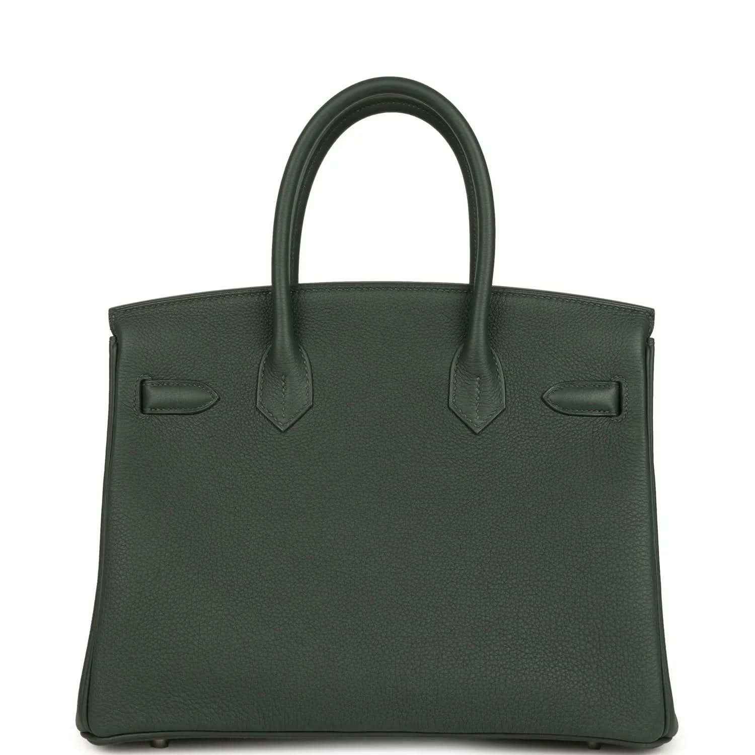 Green leather handbag with top handles and front flap details; decorative corner tabs