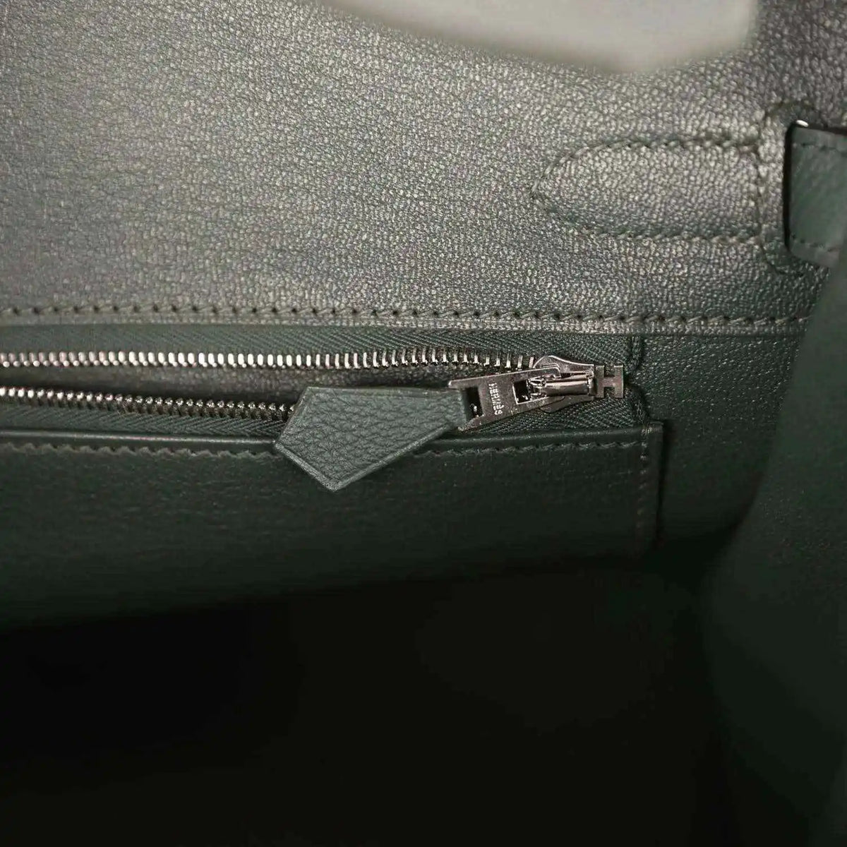 Green leather handbag interior pocket with zipper and metal pull tab