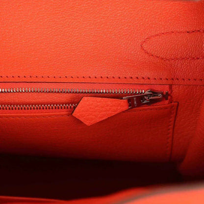 Orange handbag close-up of zipper and leather pocket with stitched edging and hardware