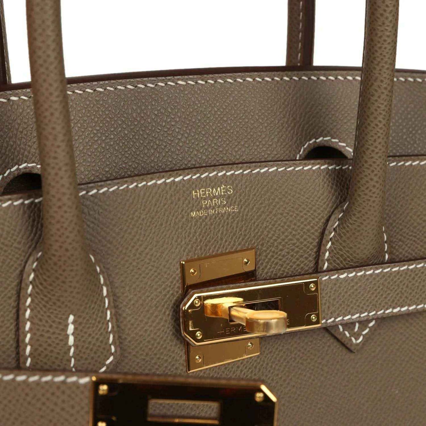 Hermes Birkin lock plate with gold-tone hardware and visible stitched leather edge
