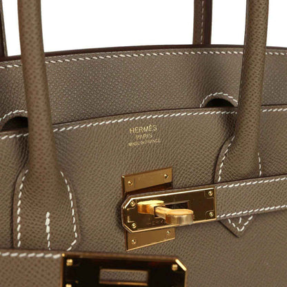 Hermes Birkin lock plate with gold-tone hardware and visible stitched leather edge
