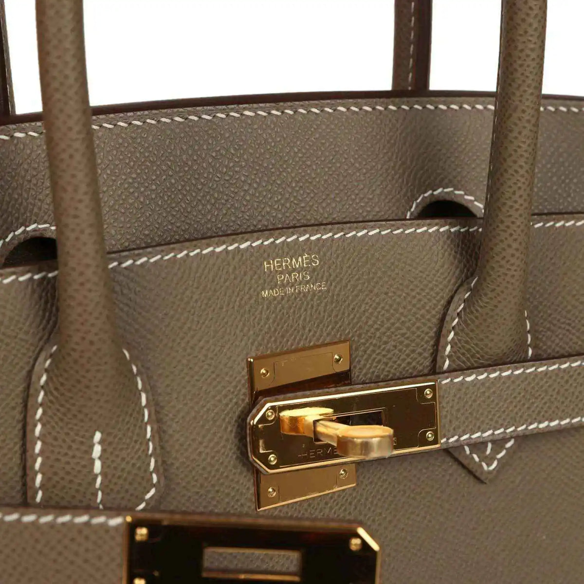 Hermes Birkin lock plate with gold-tone hardware and visible stitched leather edge