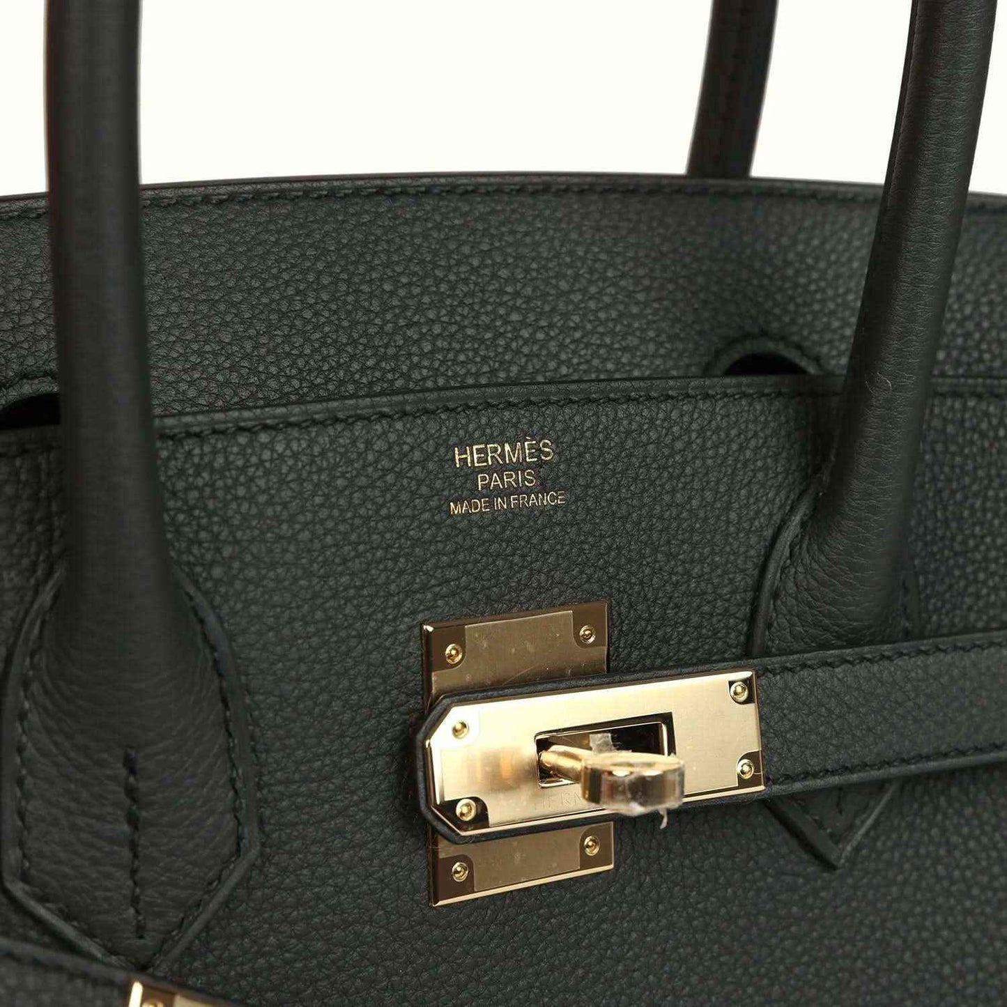 Hermes leather stamp and front turn-lock hardware on dark green handbag