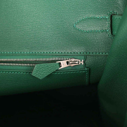 Green leather handbag interior detail with silver zipper pull and stitched seam trim