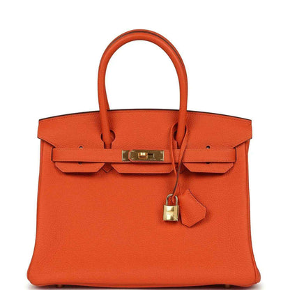 Orange leather handbag with gold-tone front clasp and top handles.