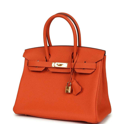 Orange leather handbag front view with gold-tone clasp and hanging lock charm.