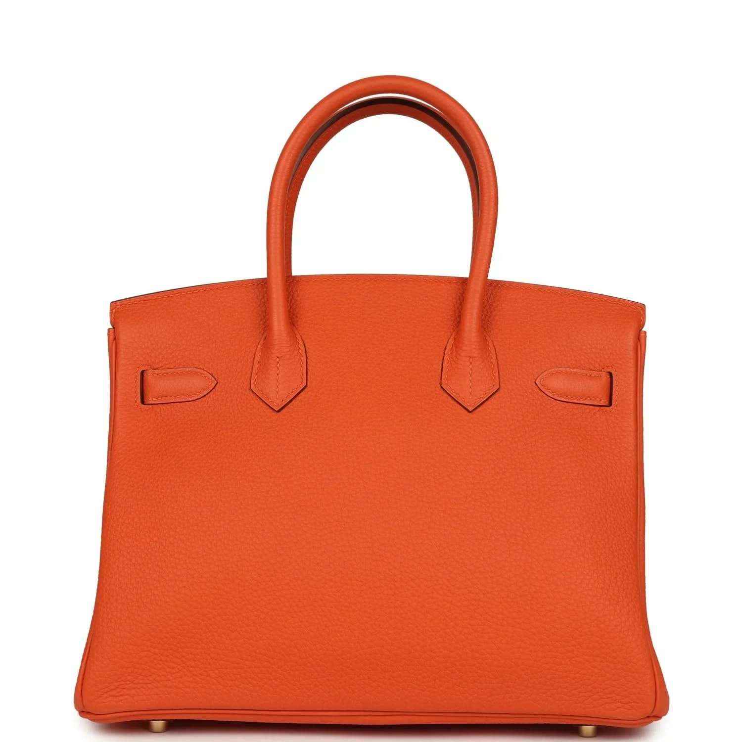Orange leather handbag back view with two top handles and minimal front hardware.
