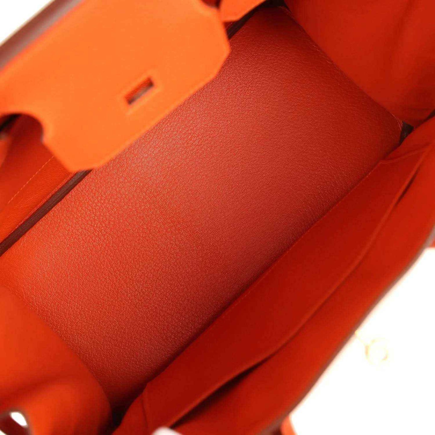 Orange leather handbag interior lining with stitch seams and structured compartments.
