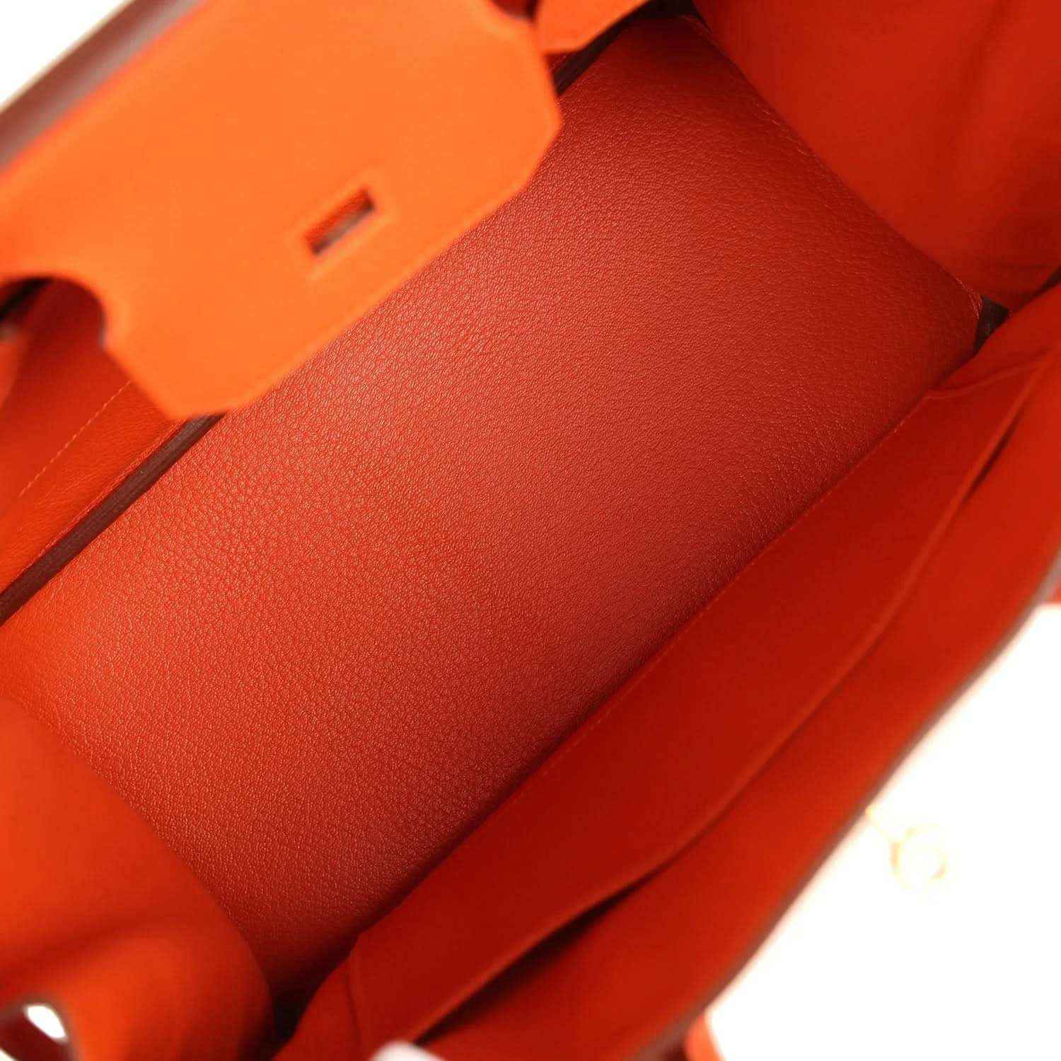 Orange leather handbag interior lining with stitch seams and structured compartments.
