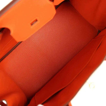 Orange leather handbag interior lining with stitch seams and structured compartments.