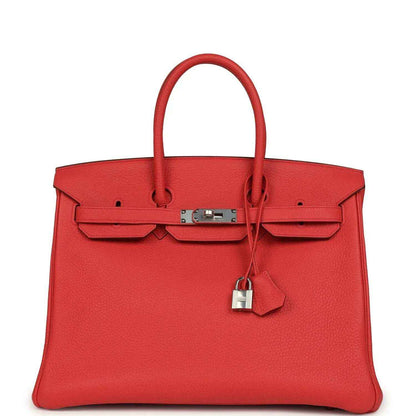 Red leather handbag with top handles, front flap pockets, and silver-tone lock