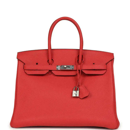 Red leather handbag with top handles, front flap pockets, and silver-tone lock
