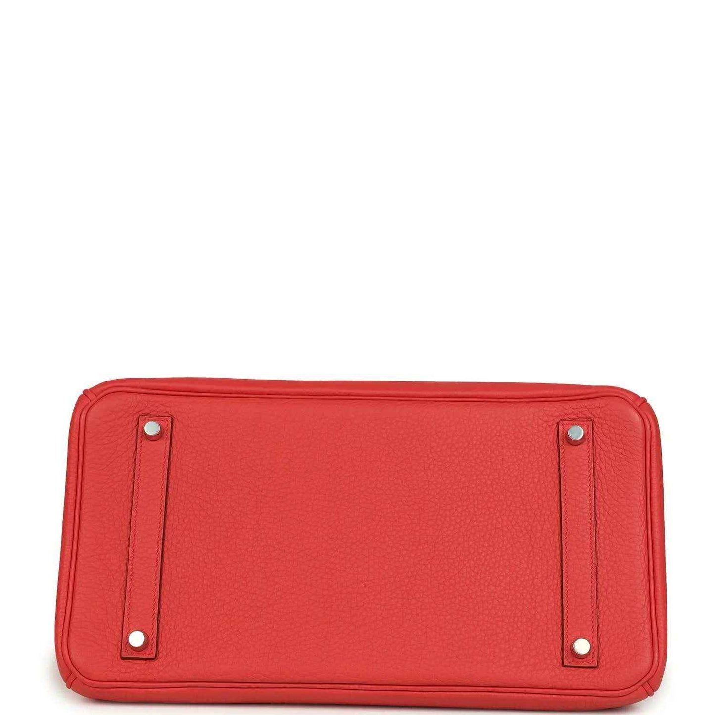 Red leather handbag with two metal studs on the rectangular bottom panel