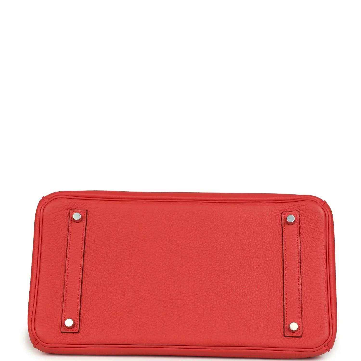 Red leather handbag with two metal studs on the rectangular bottom panel