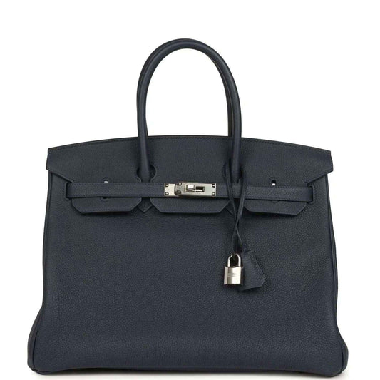 Navy leather handbag with top handle, front flap, and palladium-toned clasp