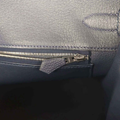Navy leather handbag interior with zip pocket, zipper pull, and stitched trim