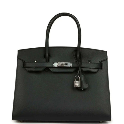 Black leather handbag with top handles, front clasp, and hanging lock charm