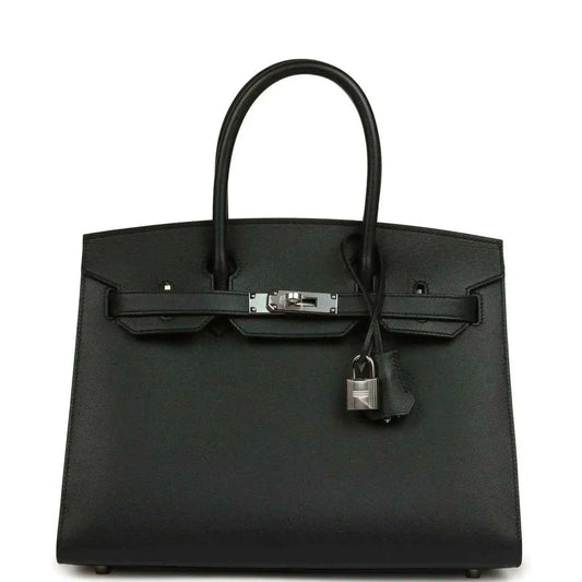 Black leather handbag with top handles, front clasp, and hanging lock charm