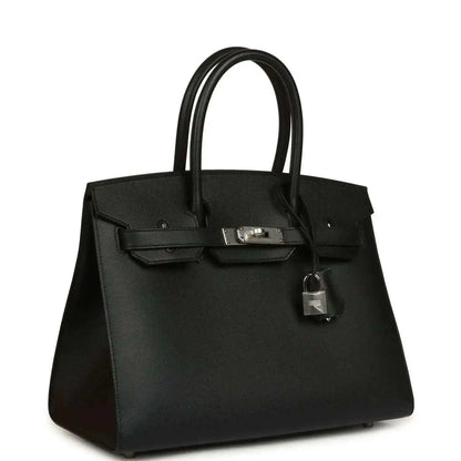 Black leather handbag with structured sides, top handles, front clasp, and hanging lock