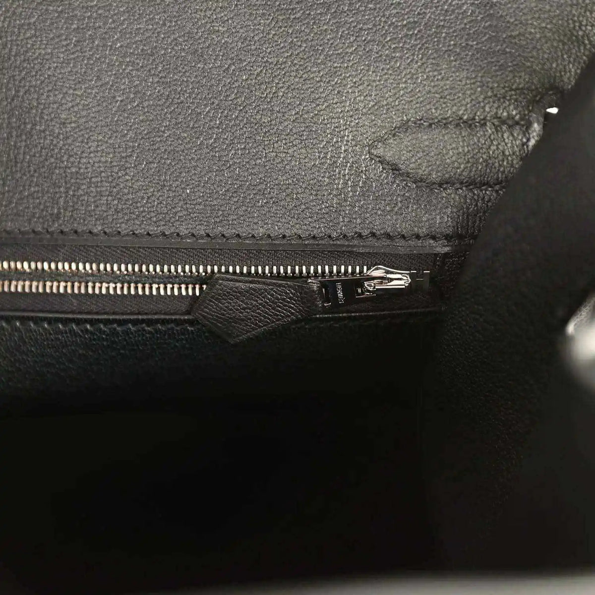 Black leather handbag interior with zipper and stitched fabric lining