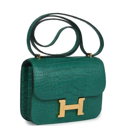 Green alligator-texture handbag with gold H clasp and long shoulder strap, side view