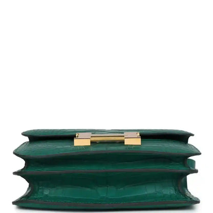Green alligator-texture handbag top view with open flap and gold turn-lock hardware